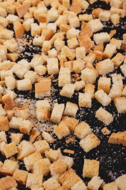 Koyu arkaplanda kavrulmuş beyaz ekmek parçaları. Lezzetli kızarmış ekmeklerin yakın çekimi..