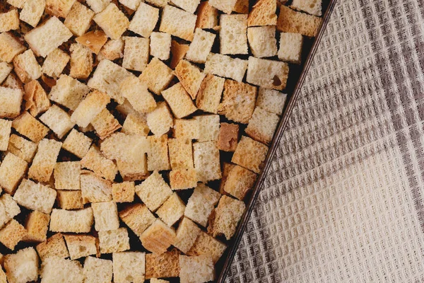 Pieces of roasted white bread in the baking tray on tablecloth. Close-up of delicious croutons.