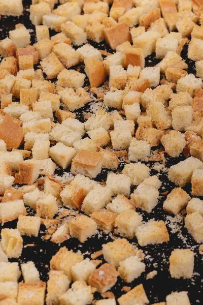 Koyu arkaplanda kavrulmuş beyaz ekmek parçaları. Lezzetli kızarmış ekmeklerin yakın çekimi..