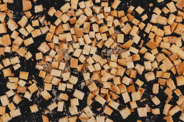 Pieces of roasted white bread on a dark background. Close-up of delicious croutons. Top view