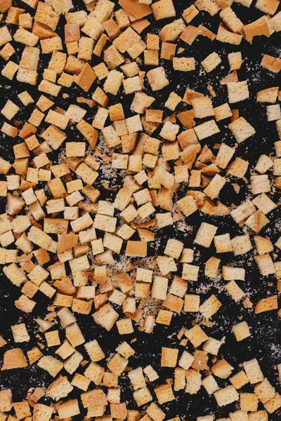 Pieces of roasted white bread on a dark background. Close-up of delicious croutons. Top view