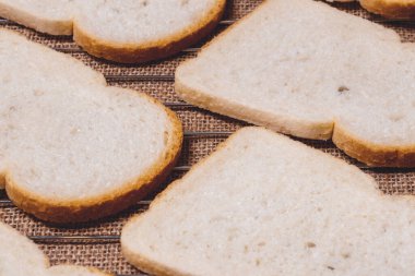 Altında çuval bezi olan ızgara ızgarasında dilimlenmiş beyaz ekmek..