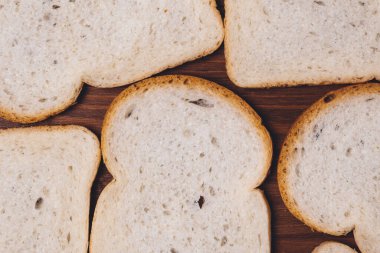 Dilimlenmiş beyaz ekmek. Kahverengi kabuklu. Koyu ahşap masaya yakın. Üst görünüm