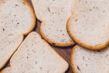 Dilimlenmiş beyaz ekmek. Kahverengi kabuklu. Koyu ahşap masaya yakın. Üst görünüm