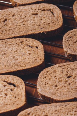 Koyu ahşap masadaki ızgarada dilimlenmiş kahverengi ekmek..