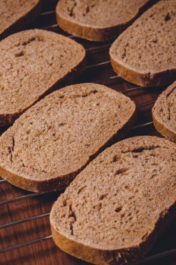 Koyu ahşap masadaki ızgarada dilimlenmiş kahverengi ekmek..