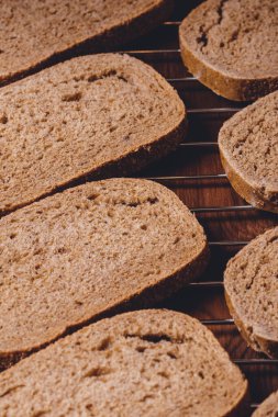 Koyu ahşap masadaki ızgarada dilimlenmiş kahverengi ekmek..