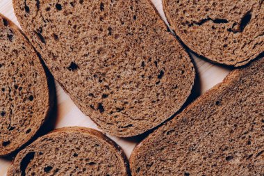 Beyaz ahşap masada dilimlenmiş kahverengi ekmek. Üst görünüm