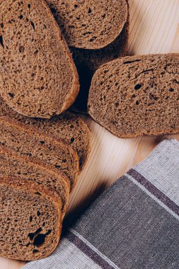 Beyaz ahşap masada dilimlenmiş kahverengi ekmek. Üst görünüm