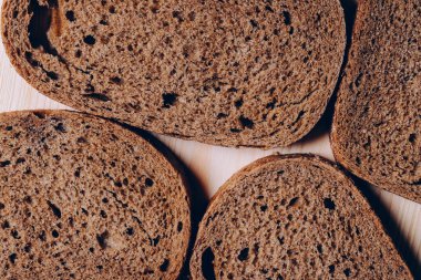 Beyaz ahşap masada dilimlenmiş kahverengi ekmek. Üst görünüm