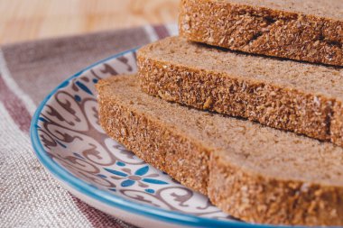 Masa örtüsünde kepek kaplı dilimlenmiş kahverengi ekmek..