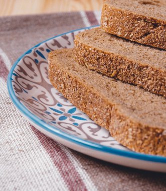 Masa örtüsünde kepek kaplı dilimlenmiş kahverengi ekmek..
