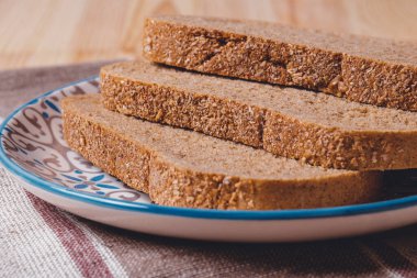 Masa örtüsünde kepek kaplı dilimlenmiş kahverengi ekmek..