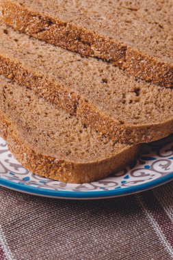 Masa örtüsünde kepek kaplı dilimlenmiş kahverengi ekmek..