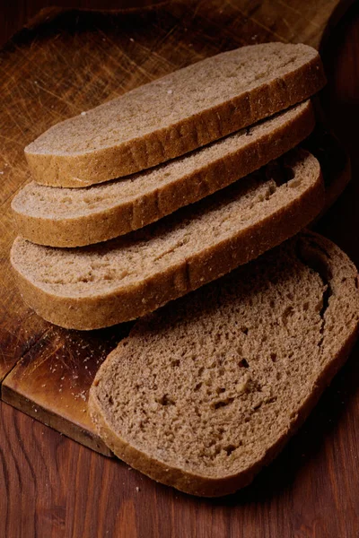 Krájený Hnědý Chléb Dřevěné Desce Tmavém Dřevěném Stole — Stock fotografie