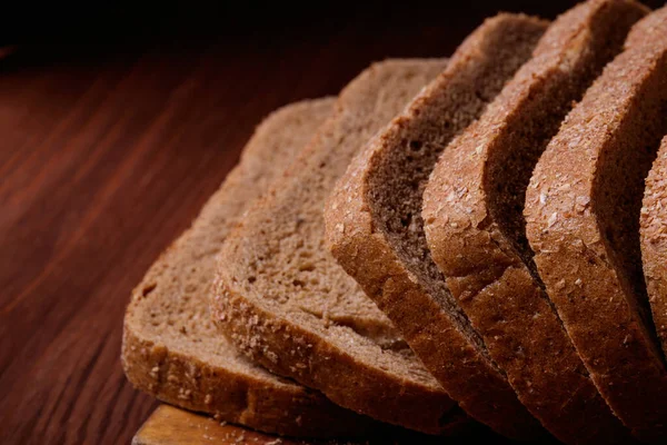 Κομμένο Καφέ Ψωμί Καλυμμένο Πίτουρο Ξύλινη Σανίδα Στο Σκούρο Ξύλινο — Φωτογραφία Αρχείου