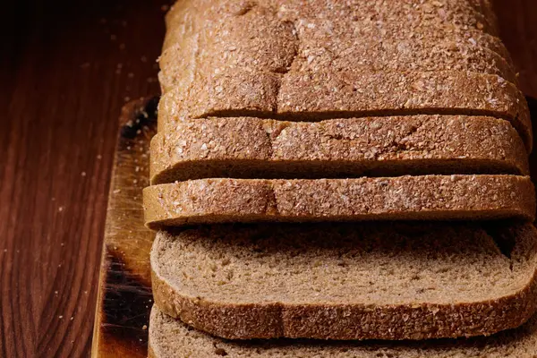 Κομμένο Καφέ Ψωμί Καλυμμένο Πίτουρο Ξύλινη Σανίδα Στο Σκούρο Ξύλινο — Φωτογραφία Αρχείου
