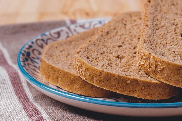 Brązowy Chleb Plasterkach Pokryty Otrębami Talerzu Obrusie — Zdjęcie stockowe