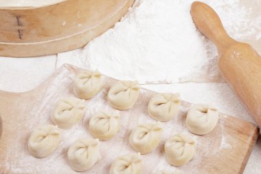 Tahtadaki hamur köfteleri, un, elek ve masanın üzerindeki merdane. Ev yapımı hamur tatlısı yakın plan..
