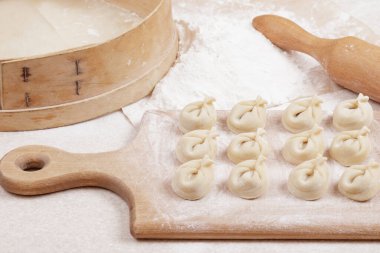 Tahtadaki hamur köfteleri, un, elek ve masanın üzerindeki merdane. Ev yapımı hamur tatlısı yakın plan..