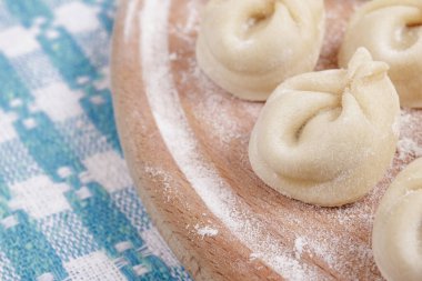 Ev yapımı çiğ hamur köfteleri kareli masa örtüsünün üzerinde tahta bir tahtanın üzerinde. Hamur köfteleri yakın plan..