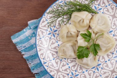 Taze maydanozla süslenmiş hamur tatlısı ve masanın üstündeki kareli peçetede dereotu..