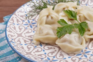 Taze maydanozla süslenmiş hamur tatlısı ve masanın üstündeki kareli peçetede dereotu..