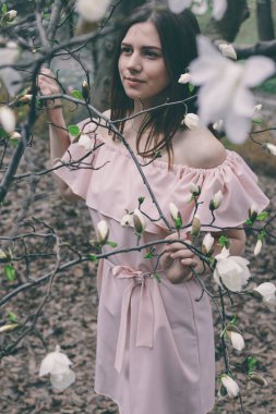 Manolya çiçekleri içinde güzel bir genç kadının portresi. Manolya çiçekli bahar kızı. Pembe elbiseli esmer kızın portresi..