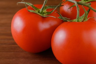 Ahşap zemin üzerinde taze, olgun kırmızı domatesler. Domates dalına yakın çekim.