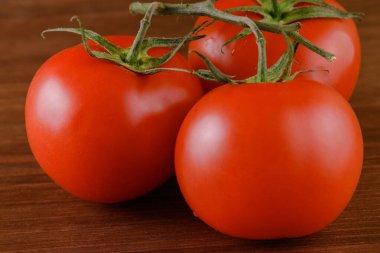 Ahşap zemin üzerinde taze, olgun kırmızı domatesler. Domates dalına yakın çekim.