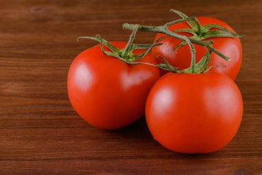 Ahşap zemin üzerinde taze, olgun kırmızı domatesler. Domates dalına yakın çekim.