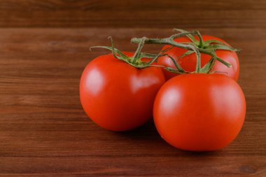 Ahşap zemin üzerinde taze, olgun kırmızı domatesler. Domates dalına yakın çekim.