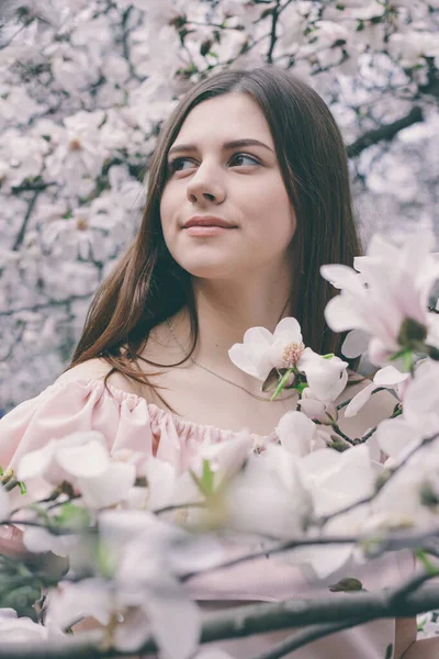 Manolya çiçekleri içinde güzel bir genç kadının yakın plan portresi. Manolya çiçekli bahar kızı. Pembe elbiseli esmer kızın portresi..