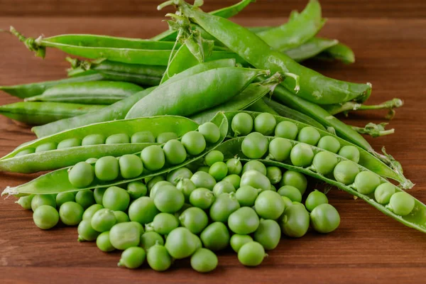 Green pea and pea pods. Pea on wooden table. Closeup of fresh pea. Pea pod with beans.