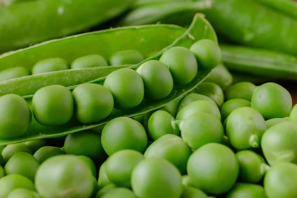 Green pea and pea pods. Peas background. Closeup, macro shot of fresh pea. Pea pod with beans.