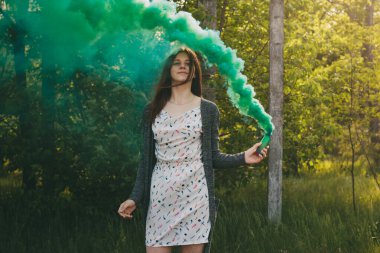 Sis bombası olan kız doymuş yeşil duman bulutları yaratıyor..