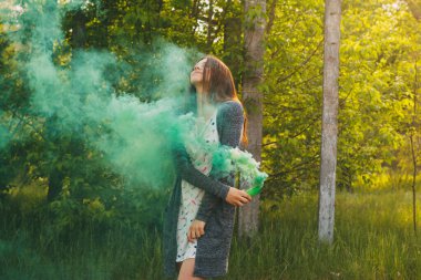 Sis bombası olan kız doymuş yeşil duman bulutları yaratıyor..