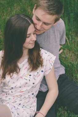 Sıcak aylarda parktaki mutlu bir çiftin portresi. Yeşil çimlerde oturan çift.