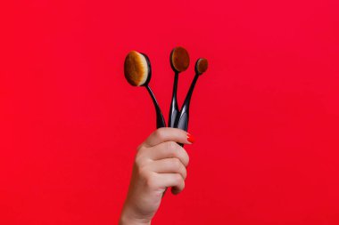 Makyaj fırçaları kadın eli kırmızı arka planda. Makyaj fırçaları ayarlandı.