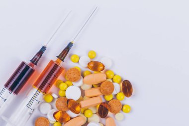 Çok renkli haplar, haplar ve beyaz arka planda sıvı bulunan tıbbi şırınga. Makro. Tıbbi konsept. Üst görünüm.