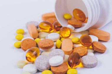 Plastik hap şişesinden beyaza saçılmış çok renkli haplar ve haplar. Çeşitli tedaviler. Çeşitli ilaçlar ve haplar. Kapatın. Makro. Tıbbi konsept.