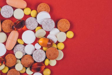 Kırmızı arka planda haplar ve haplar. Çeşitli tedaviler. Çeşitli ilaçlar ve haplar. Kapatın. Makro. Üst Manzara. Tıbbi konsept.