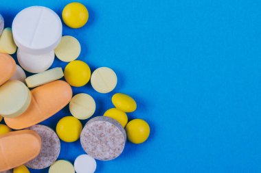Tabletler ve haplar mavi arka planda. Çeşitli tedaviler. Çeşitli ilaçlar ve haplar. Kapatın. Makro. Üst Manzara. Tıbbi konsept.