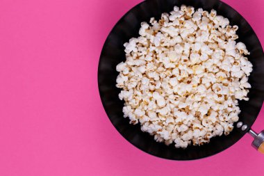 Pembe arka plandaki tavada patlamış mısır..