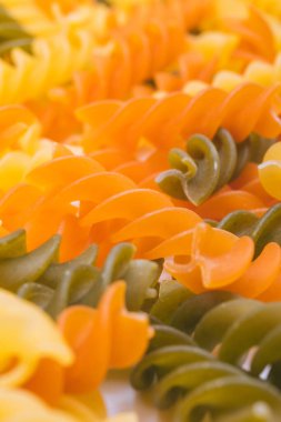 Üç renkli Fusilli makarnası. Pişmemiş renkli makarnadan makro shot..