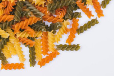 Beyaz arka planda üç renkli makarna yığını. Yakın plan. Üst görünüm.