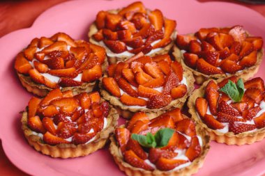 Taze çilekli turtalar tabakta yakın plan. Nane yapraklarıyla süslenmiş tartlar..