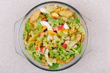 Yengeç çubuklu salata, domates, Napa lahanası, yumurta, marul ve cam kasede kızarmış ekmek. Üst görünüm.