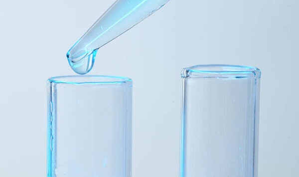 Drop from pipette drips into laboratory test tubes.