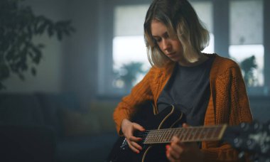 Genç kız yarı akustik gitar çalmayı öğreniyor..